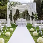 White wedding arch with chiffon drape and white floral arrangements
